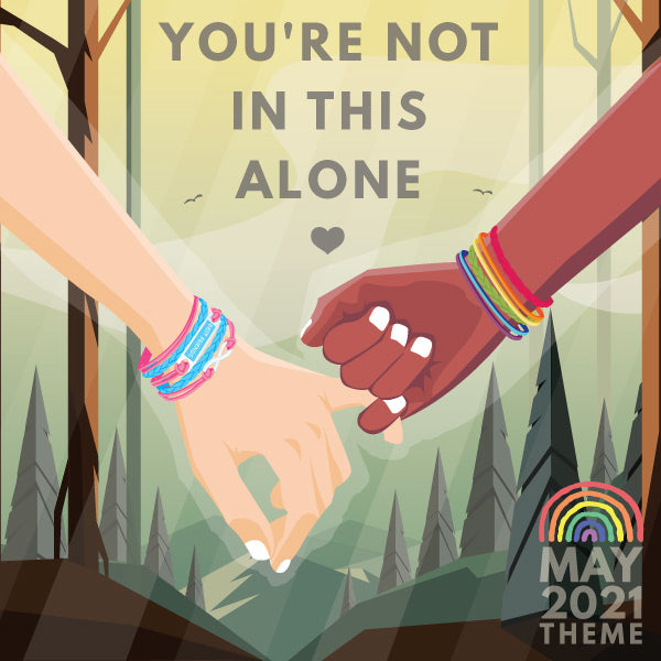 Our May 2021: You're not in this alone theme image, which features two hands grasping in front of a sunlit forest.